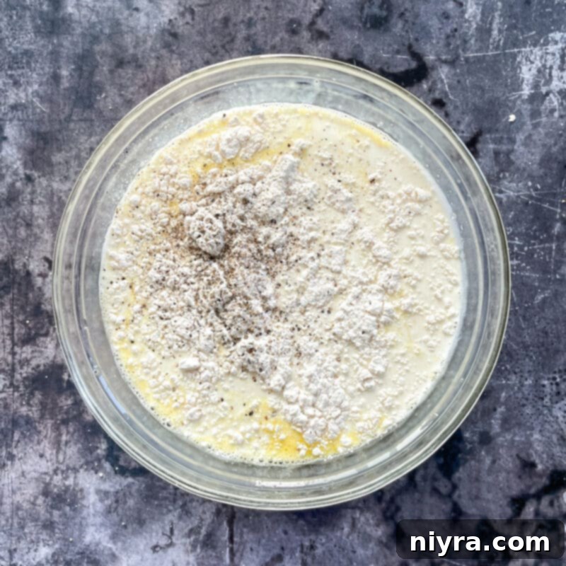 A perfectly rolled breakfast enchilada, seam-side down in the baking dish with others, ready for the sauce.