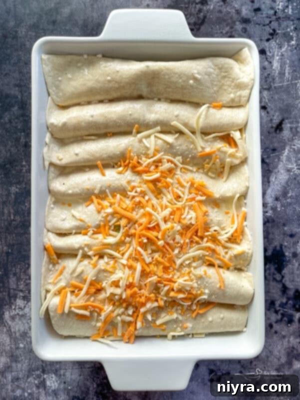 The egg and cream mixture being poured over the rolled ham enchiladas in a baking dish.