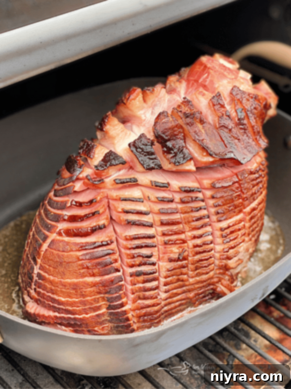 A perfectly glazed smoked ham cooking on a smoker, ready for a delicious meal.