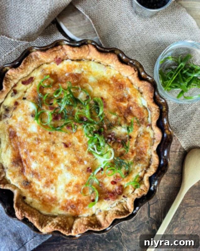 Overhead shot of a rich, golden brown Bacon & Swiss Quiche in a ceramic pie dish, ready to serve.