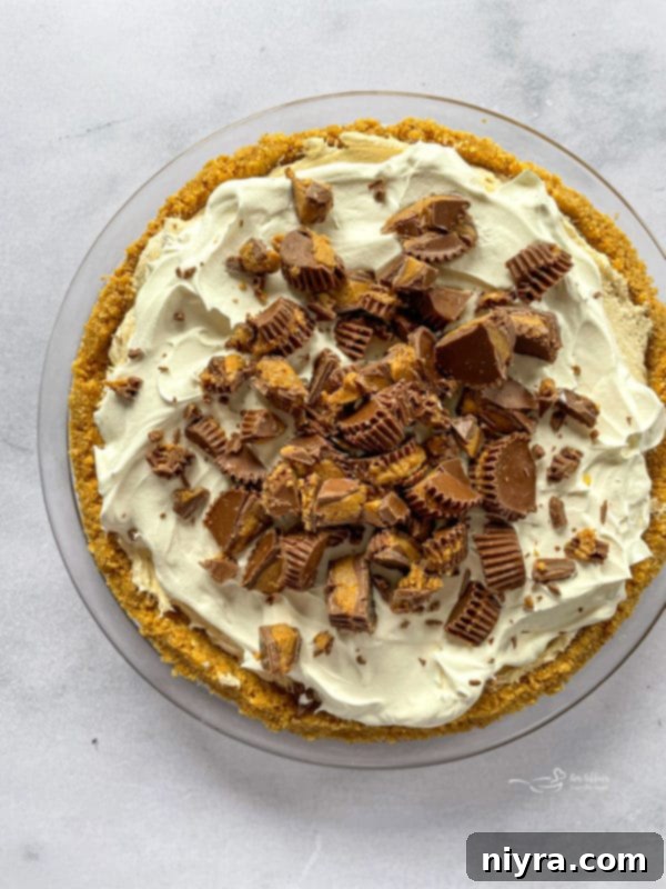 Sprinkling chopped Reese's Peanut Butter Cups over the pie
