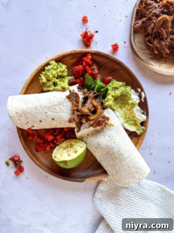 Close-up of a delicious Crock Pot Shredded Beef Burrito, showing the rich, tender beef filling wrapped in a warm tortilla, with fresh cilantro scattered around.