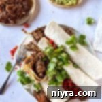 A shredded beef burrito opened so you can see the inside, highlighting the rich filling.