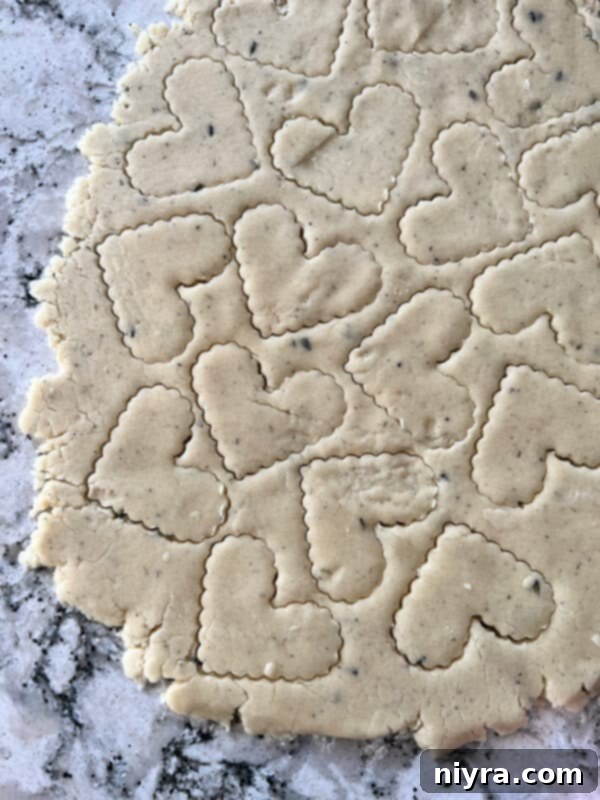 Lavender Shortbread and Lavender Strawberry Dream 14 Shortbread dough being rolled out evenly with a rolling pin on a parchment-lined surface.