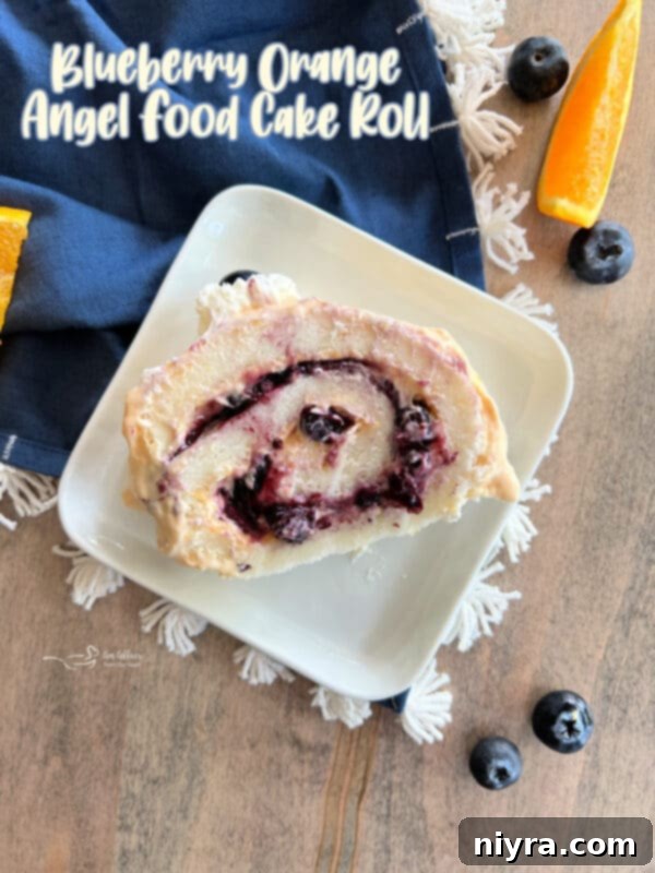 The stunning hero shot of a complete Blueberry Orange Angel Food Cake Roll, decorated and ready for serving