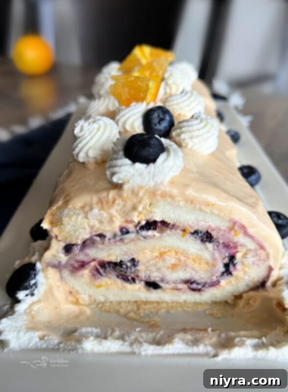 Close up of a slice of Angel Food Cake Roll revealing blueberry pie filling and orange cream cheese layers