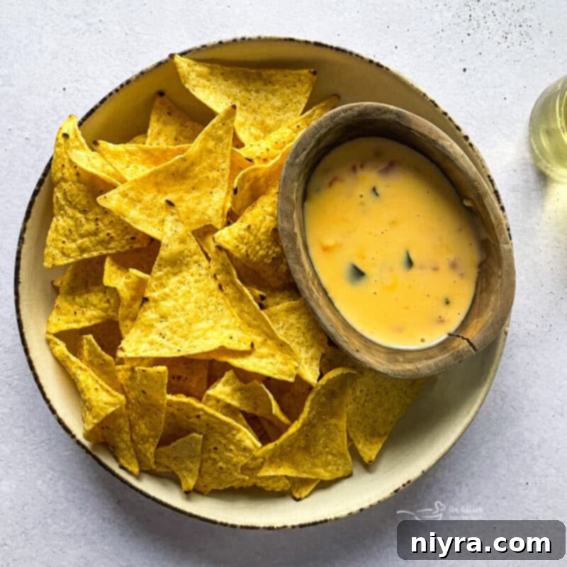 A large bowl of Qdoba Queso Dip surrounded by crunchy tortilla chips