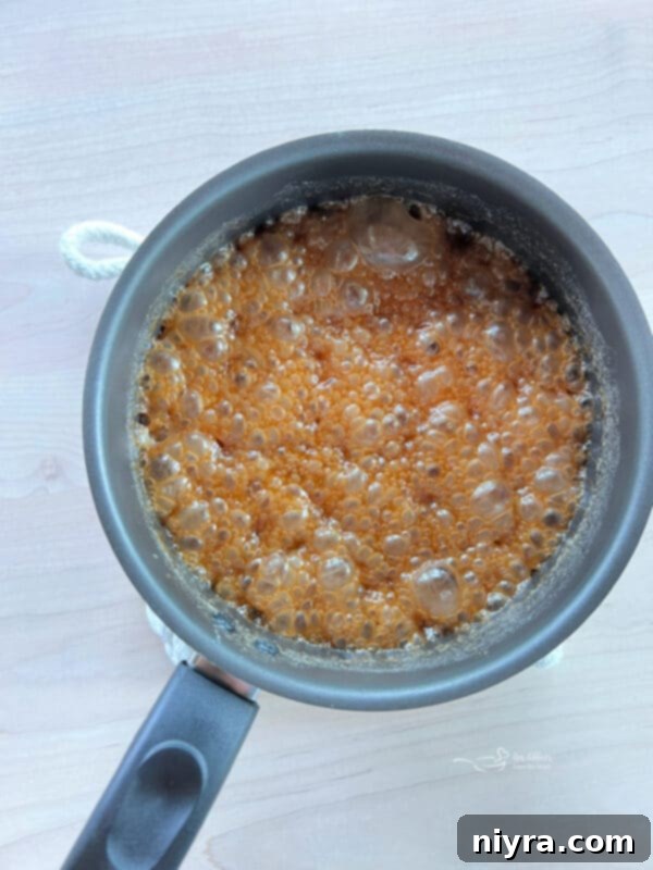 Ultimate Homemade Caramel Chocolate Nut Popcorn 13 Caramel sauce boiling vigorously in a saucepan on the stove