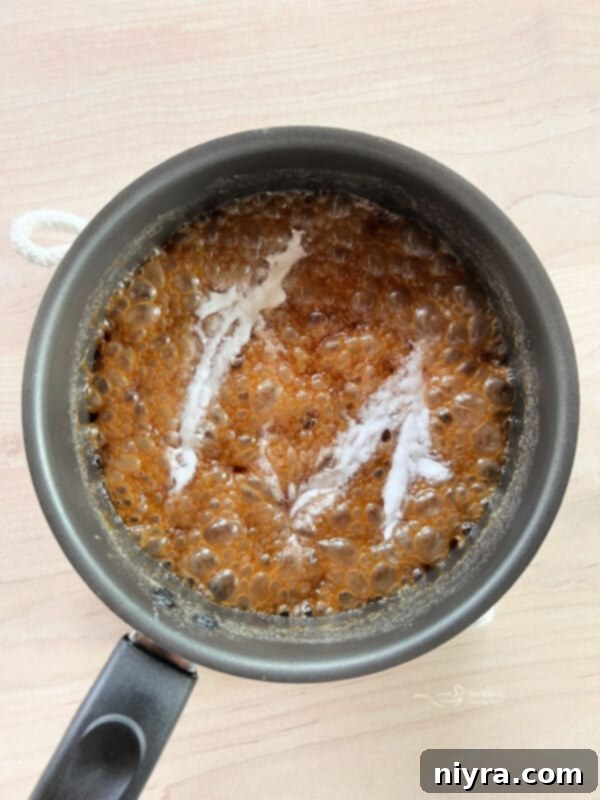 Ultimate Homemade Caramel Chocolate Nut Popcorn 14 Baking soda being stirred into the hot, bubbling caramel sauce