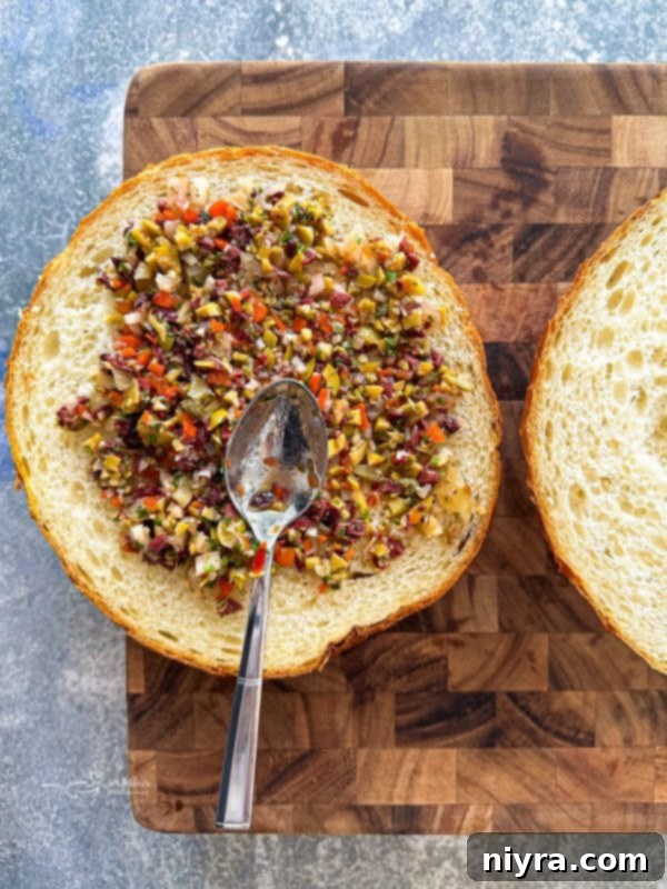 New Orleans Iconic Muffuletta 10 Spreading olive mixture on Muffuletta bread