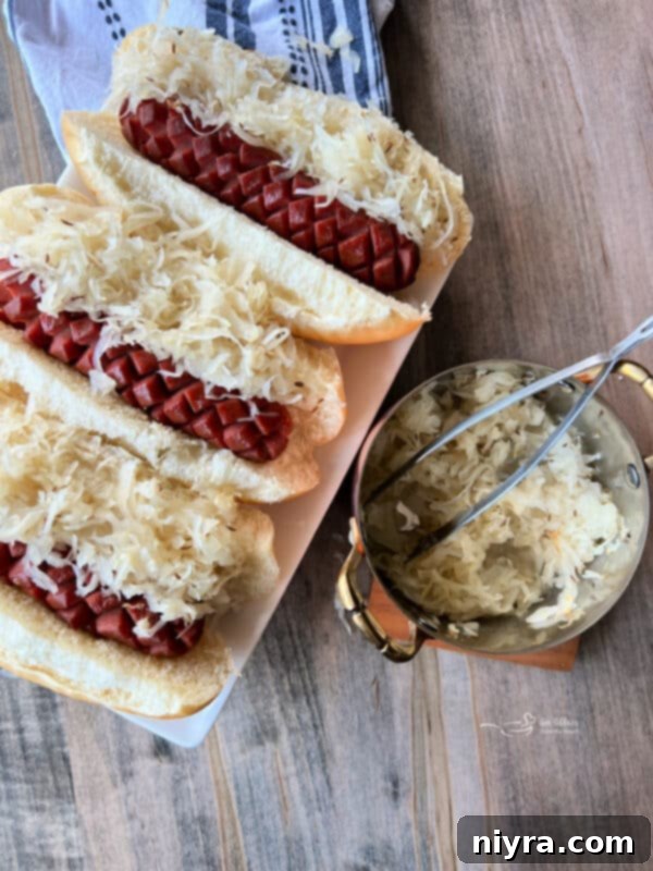Smoky Dogs with Zesty Kraut 3 Close-up of a smoked hot dog in a bun, topped with Frank's Kraut and caraway seeds