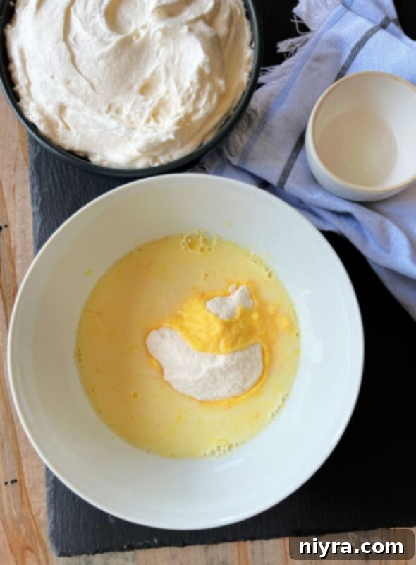 Step one of making fruit dip: Instant vanilla pudding powder and milk are being whisked together in a small mixing bowl, forming a smooth mixture.