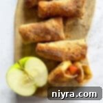 Air Fryer Apple Pie Egg Rolls and half an apple on a wood board