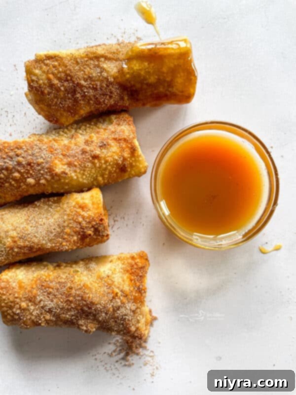 Golden brown apple pie egg rolls in an air fryer basket