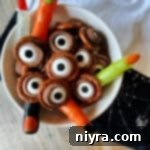 rolo pretzel eyeballs and plastic witches fingers in a white serving bowl.