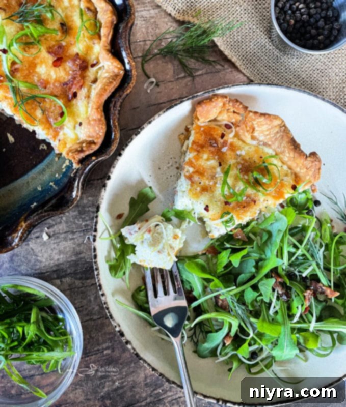 A close-up of a slice of Bacon and Swiss Quiche on a rustic wooden board.