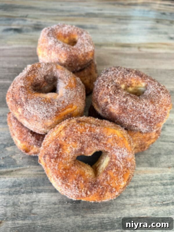 Pumpkin Spice Air Fryer Biscuit Donuts on a white plate with a fork, ready to be enjoyed