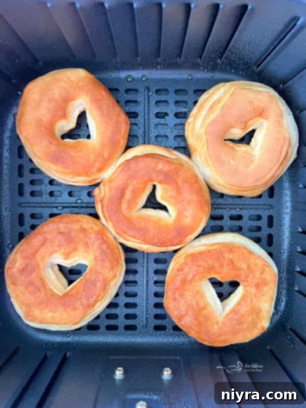 Biscuit donuts placed in a single layer in the air fryer basket, ready for cooking