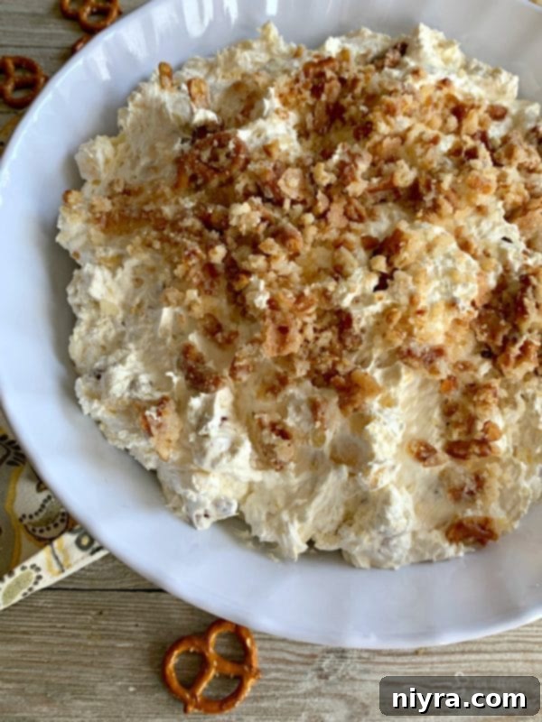 Crunchy Creamy Pineapple Cloud 6 Pineapple Pretzel Fluff being stirred in a large bowl, showcasing its creamy and chunky consistency.
