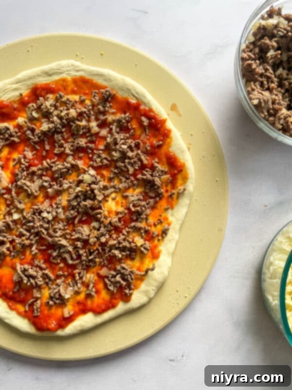 Pizza dough topped with sauce and ground beef mixture.