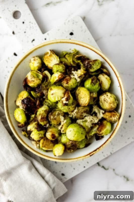 A serving of cooked Air Fryer Brussels Sprouts with Parmesan on a white plate.