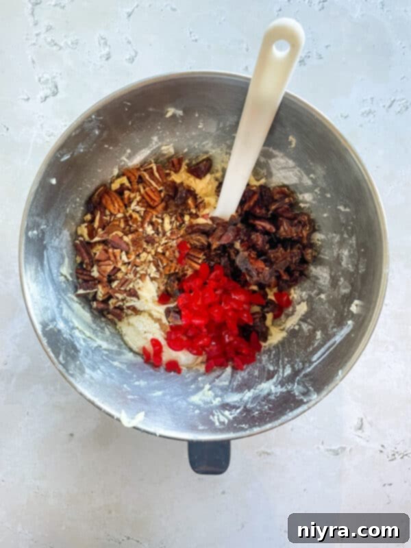 Adding chopped pecans, dates, and cherries to the cookie dough.