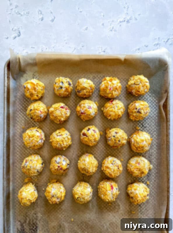 Cookie dough balls being rolled in crushed cornflakes.