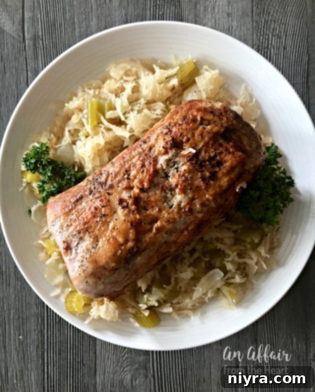 Overhead of Pork Roast & Sauerkraut on a white plate, garnished with parsley