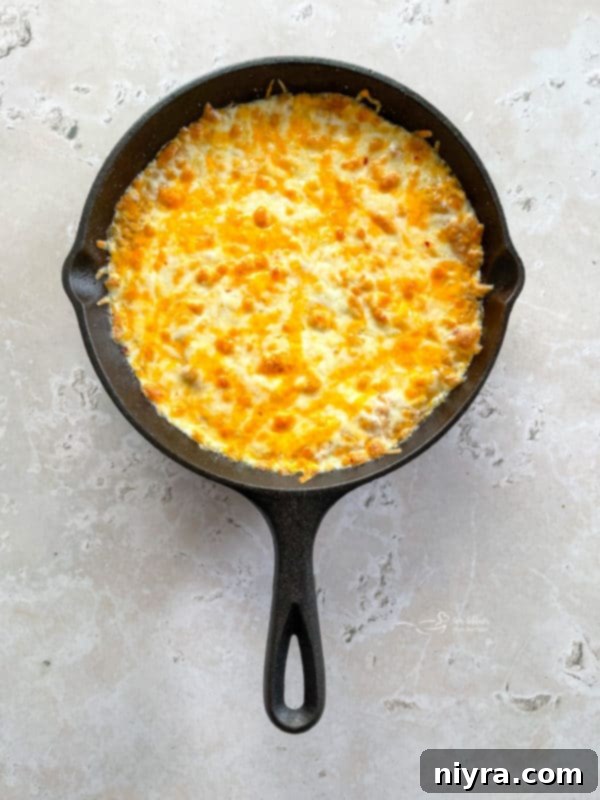 a hot skillet full of bean dip with melted cheese on top