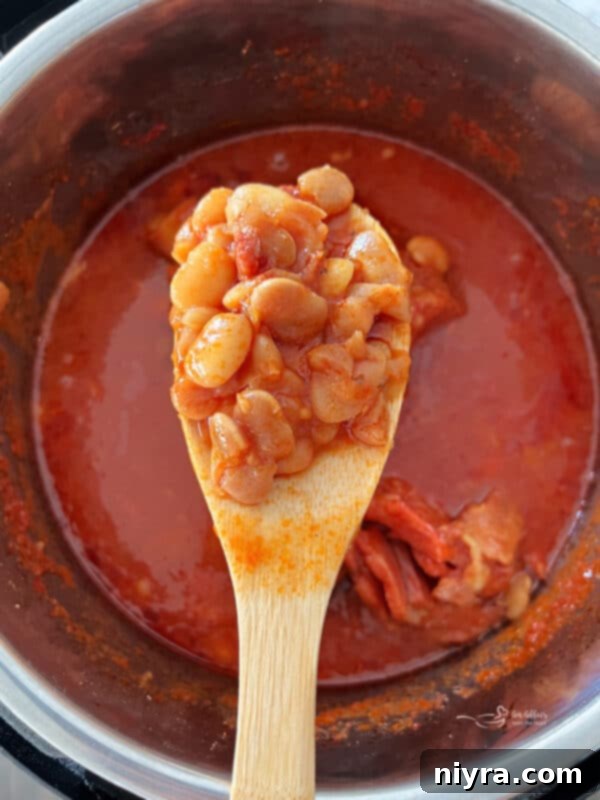 Grandmas Hearty Instant Pot Ham and Bean Soup 8 A wooden spoon scooping Instant Pot Ham and Bean Soup, showing ham and beans