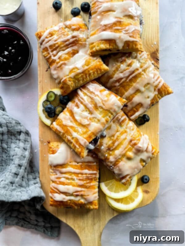 Freshly baked homemade blueberry toaster strudels on a cooling rack, drizzled with sweet icing.