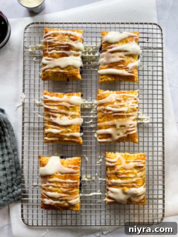 Homemade blueberry toaster strudels cooling on a rack before icing.