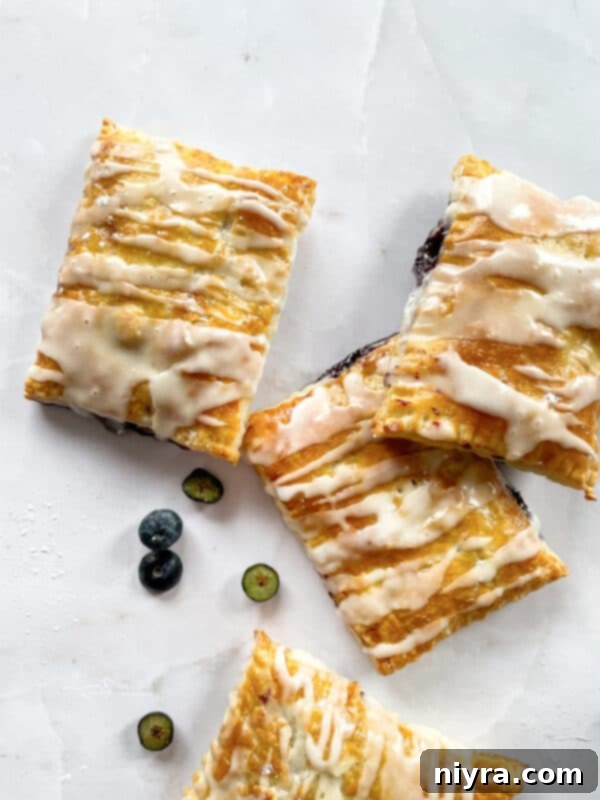A batch of unbaked homemade blueberry toaster strudels, filled and sealed, on a baking sheet.
