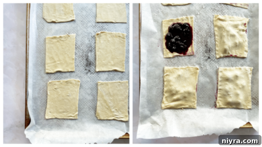 Puff pastry rectangles being filled with blueberry mixture on a baking sheet.