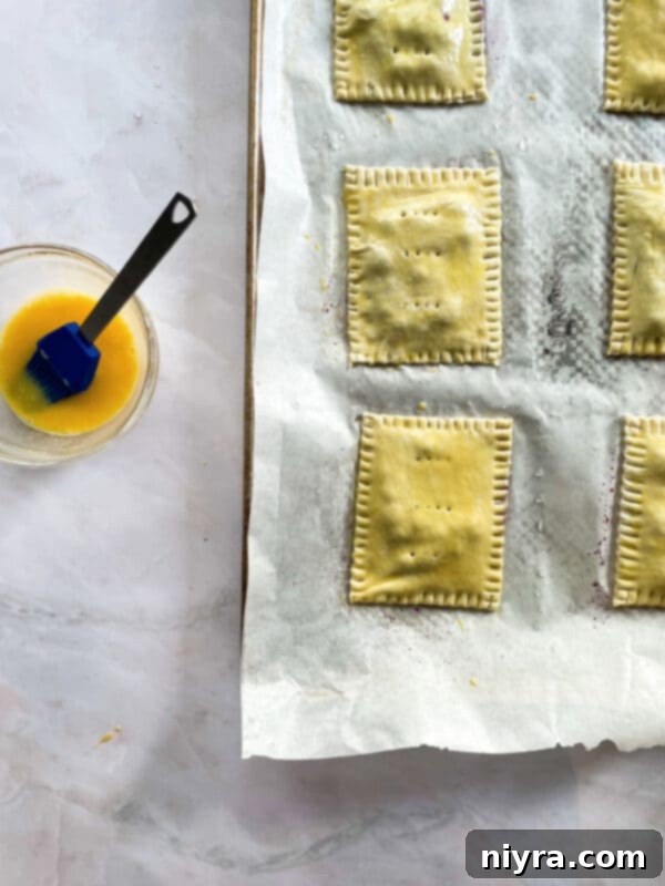 Unbaked homemade blueberry toaster strudels, brushed with egg wash, ready for the oven.