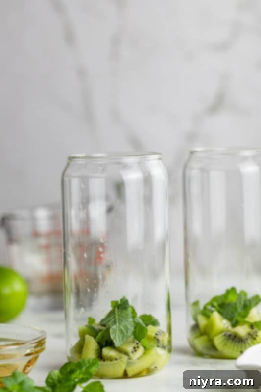 Refreshing Kiwi Mojito 6 Second step: Adding lime juice, mint leaves, and honey to kiwi in a glass