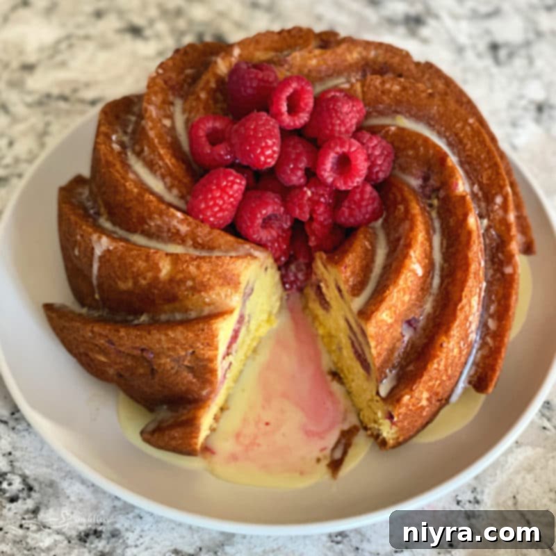 Whole Lemon Raspberry Bundt Cake topped with glaze and fresh raspberries