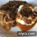 Mushroom Smothered Salisbury Steak 19 overhead of salisbury steak with mushrooms and mashed potatoes on a white plate