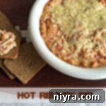 Hot Reuben Dip in a white pot with a scoop on rye toast, highlighting the "Hot Reuben Dip" text