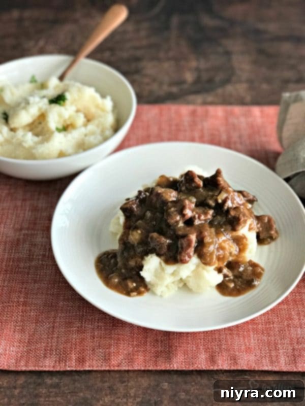 Delicious Beef Tips & Gravy served over creamy mashed potatoes, garnished for a comforting meal.
