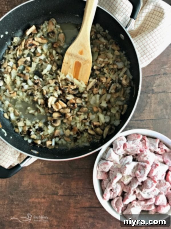 Sautéed mushrooms, onions, and garlic in a pan, ready to be removed for the next step of the recipe.