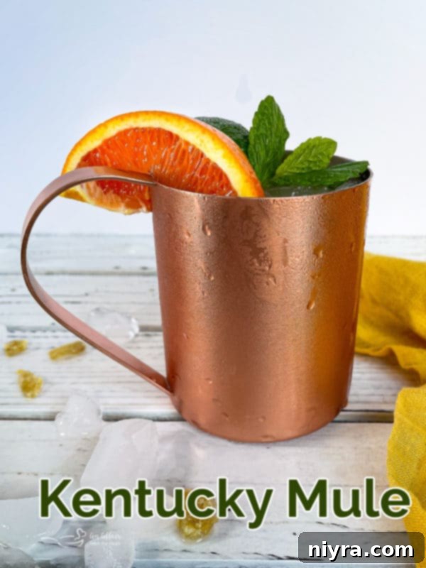 Two Kentucky Mule cocktails in copper mugs on a wooden surface.