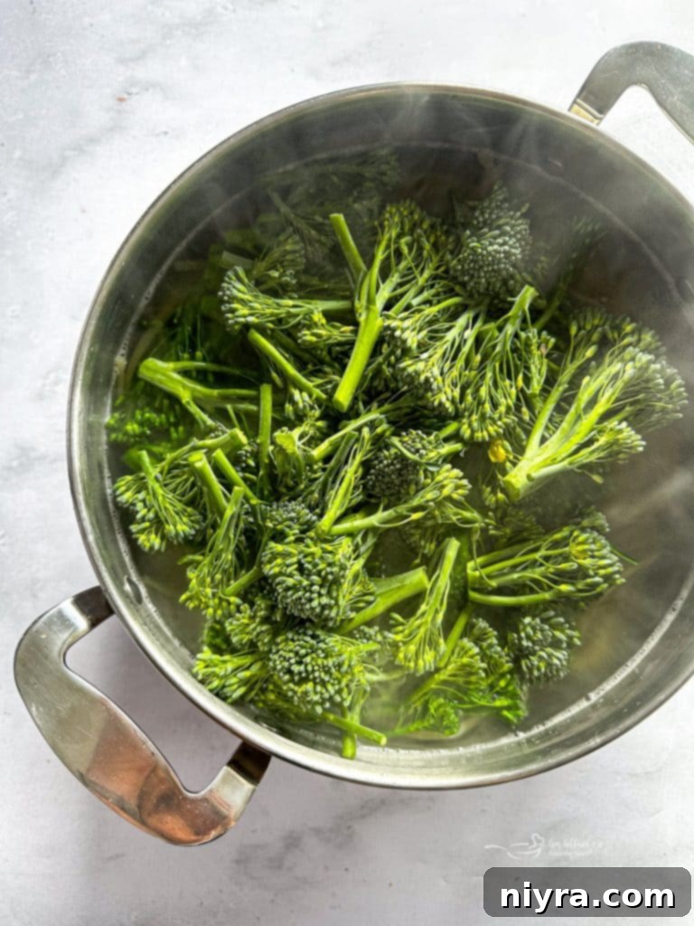 A large pot of boiling water with linguine and broccolini cooking.