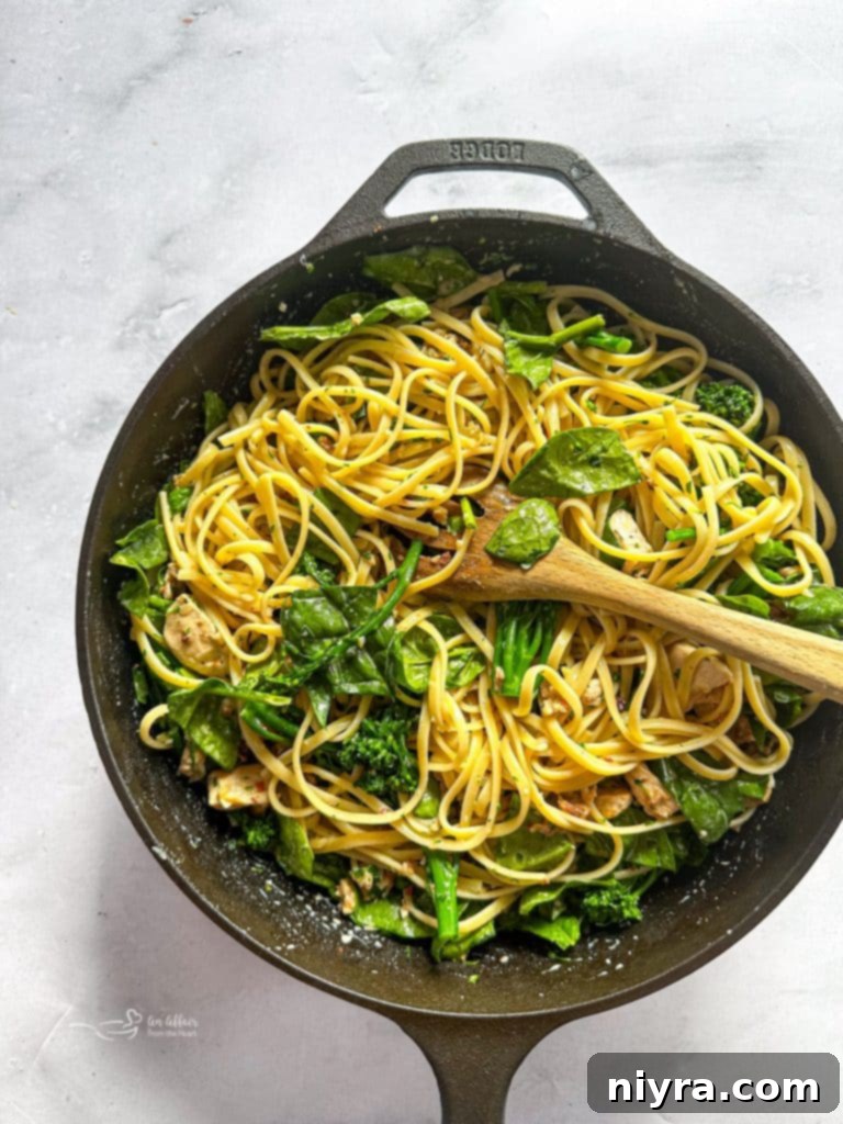 Fresh spinach and parsley being added to the creamy carbonara sauce and pasta, ready to be tossed.