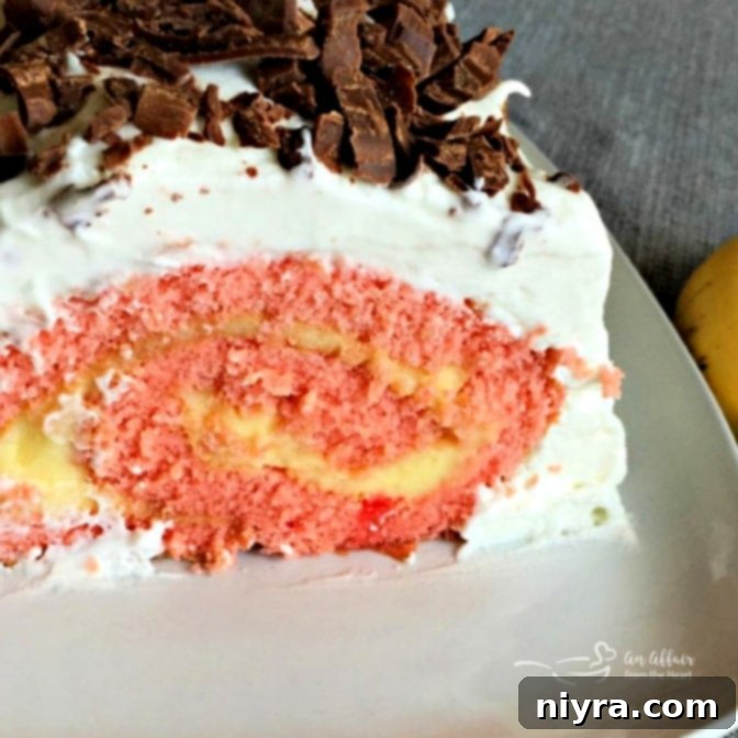 Banana Split Swirl Cake 4 A close-up view of a slice of Banana Split Jelly Roll Cake, highlighting the layers of strawberry cake, banana pudding, whipped cream, and chocolate curls.