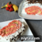 Banana Split Swirl Cake 9 Slice of Banana Split Jelly Roll Cake on a white plate and the rest of the roll on a white platter