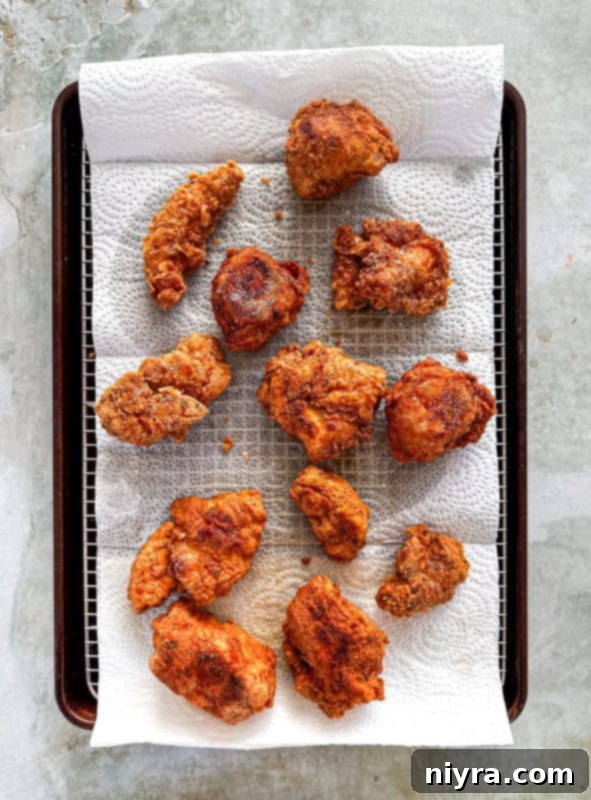 A meat thermometer inserted into a piece of crispy fried chicken to check its internal temperature.