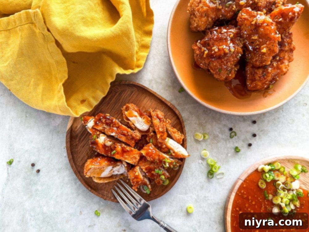 Overhead shot of honey fried chicken on a serving tray with a bowl of honey sauce and fresh green onions.