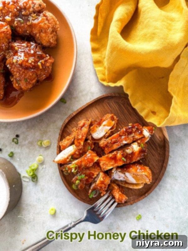 A generous serving of crispy honey fried chicken on a white plate, glistening with sweet sauce and ready to be devoured.