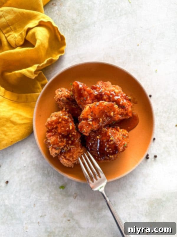 A vibrant platter of crispy honey fried chicken, garnished with fresh herbs, ready to be served.